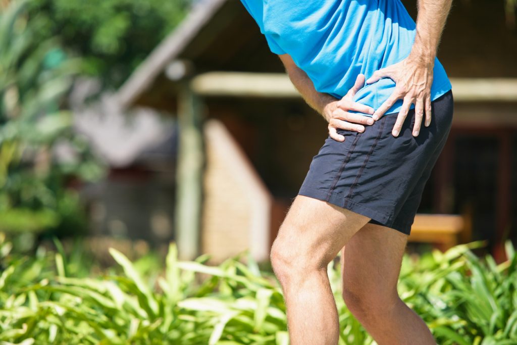 man i shorts framåtböjd håller sig om höften